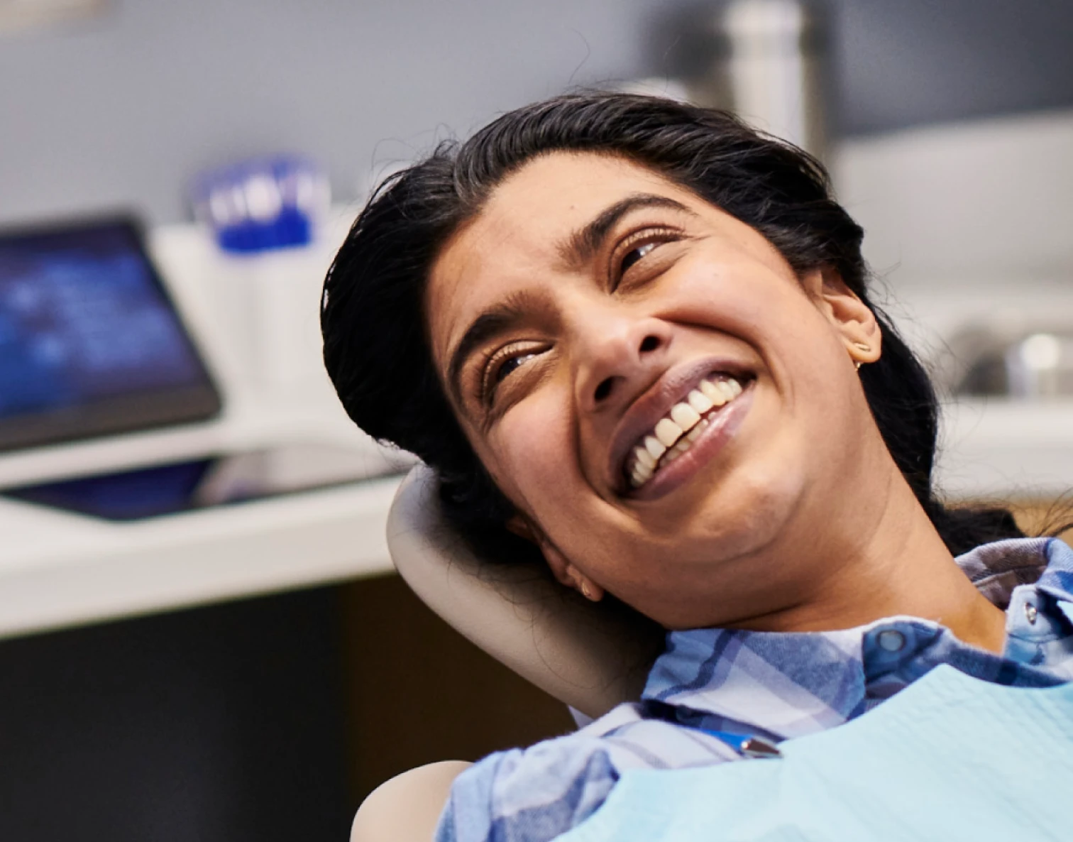 An Aspen Dental patient smiles in an examination chair. 