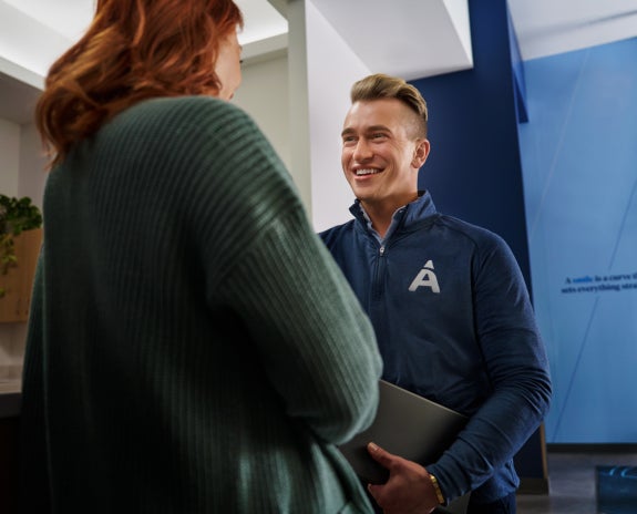 A patient consulting with a friendly Aspen Dental team member in a modern clinic setting, discussing recovery and support options after dental implant surgery.