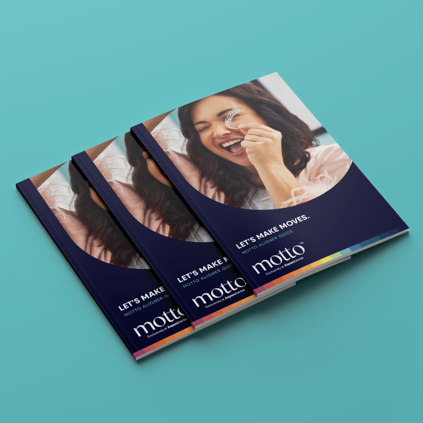 A woman holding clear aligners in her hand on a group of three booklets titled 'Let's make moves. Motto aligner guide' on a blue table.
