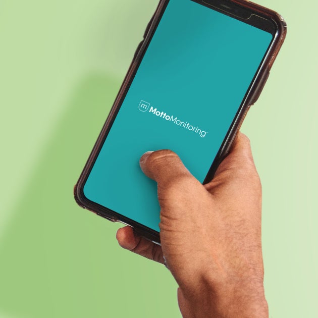 A smartphone is held in someone's hand with MottoMonitoring open. 
