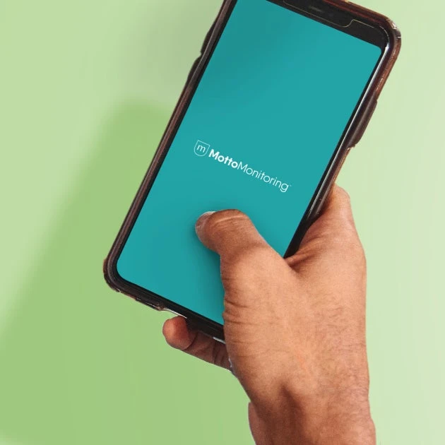 A smartphone is held in someone's hand with MottoMonitoring open.