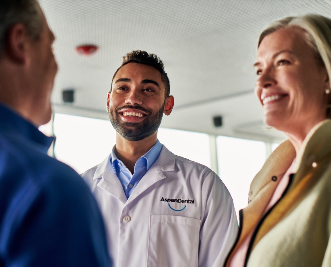 Dentist smiling while consulting with patients about suitable foods to eat after oral surgery, emphasizing personalized care and recovery guidance.