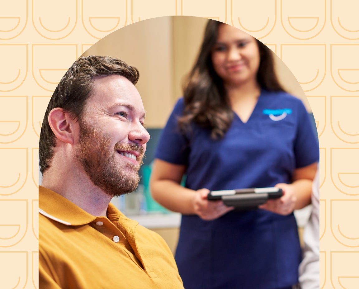 Smiling man with female Aspen Dental specialist, arch design in background.