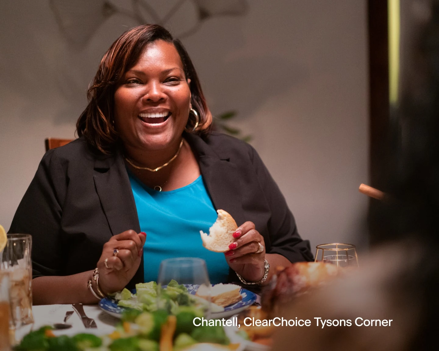 A woman is sitting at a table eating a piece of bread