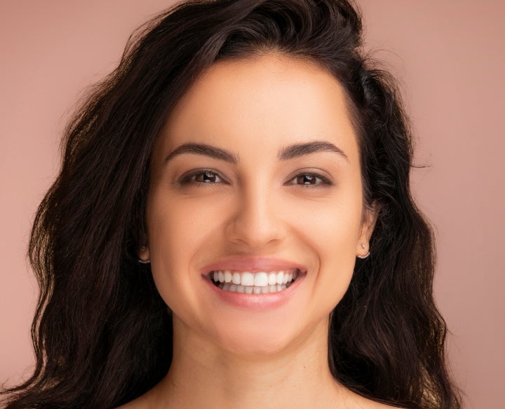 A woman with long dark hair is smiling for the camera
