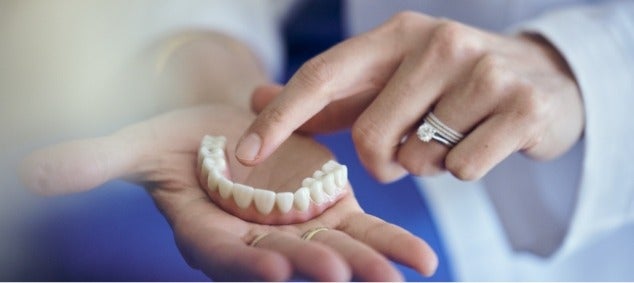 A person is holding a denture in their hand