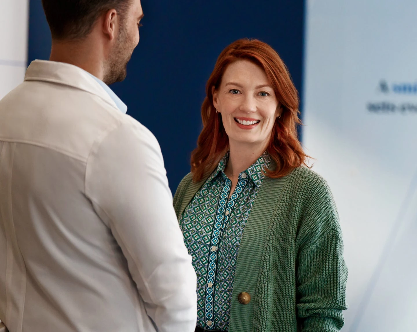 Smiling Aspen Dental patient in a green sweater interacting with a dentist during a consultation.