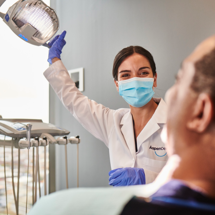 An Aspen Dental doctor moves a light to begin a dental exam. 