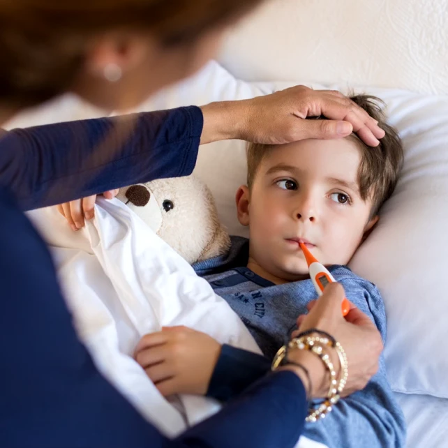 A child has their temperature taken while lying in bed. 