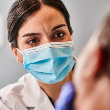 Aspen Dental dentist takes a closer look at the patient's mouth to check for any red, swollen, or bleeding gums, indicating potential gum disease or infection.