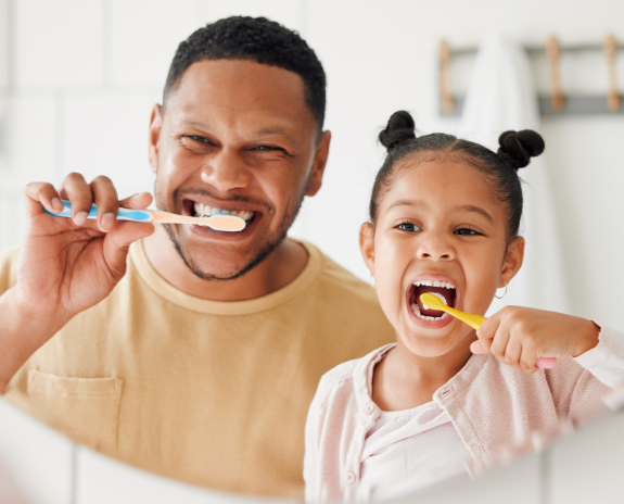 A man and his daughter practicing oral hygiene by brushing their teeth.