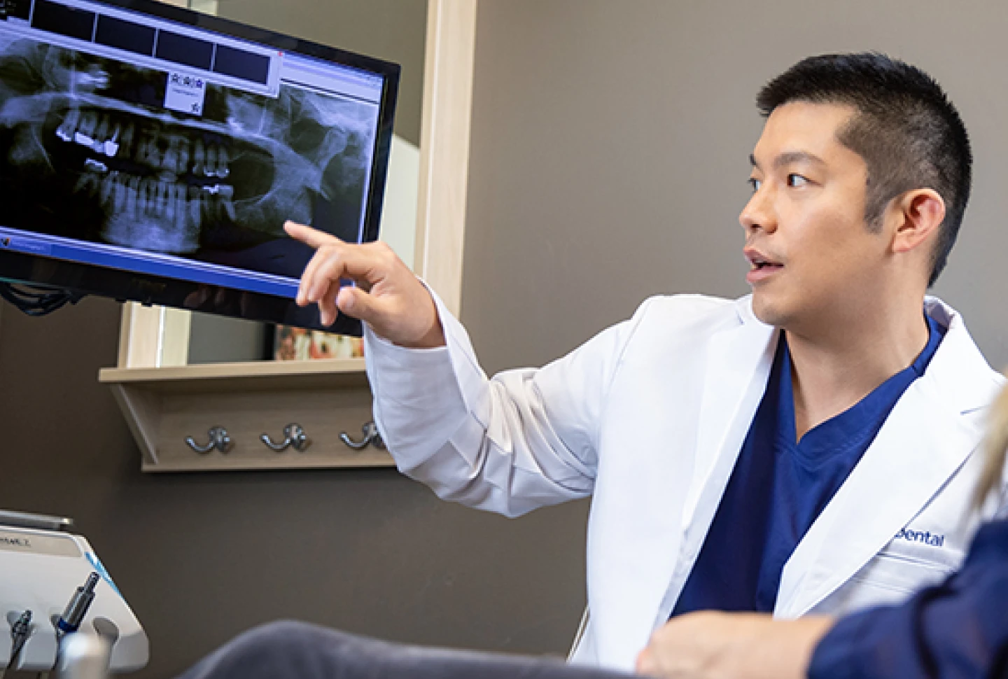 An Aspen Dental dentist reviewing dental X-rays with a patient, discussing oral health and treatment options on a computer screen.