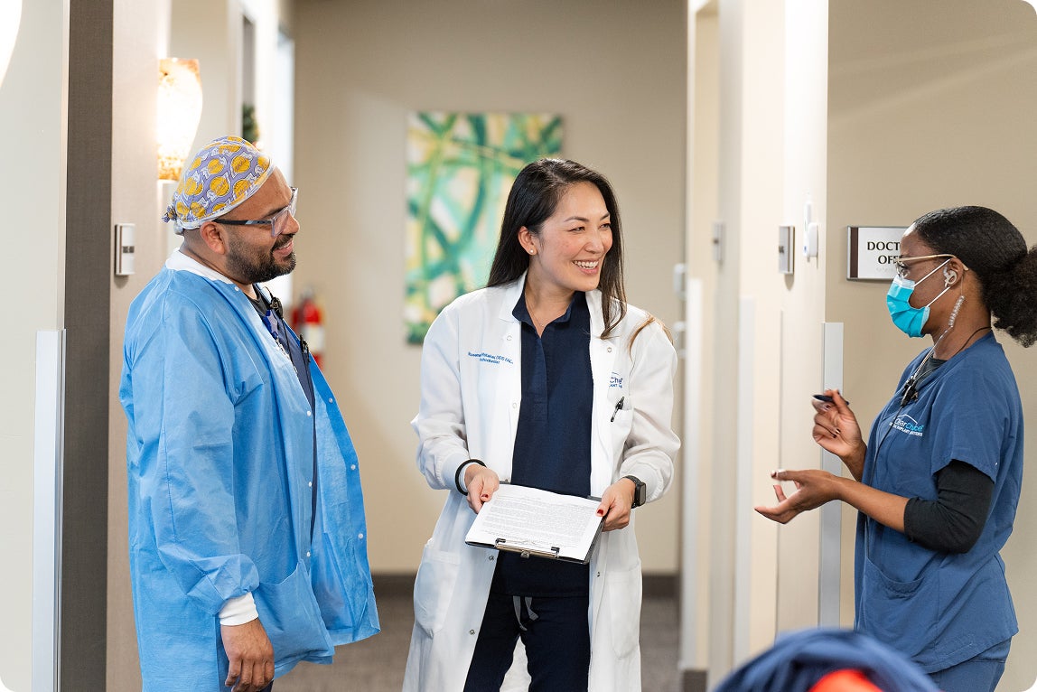 Dental implant team in a Fort Lauderdale dental office discussing a patient case in the hallway, representing experienced implant dentists and specialists in Fort Lauderdale, Florida.