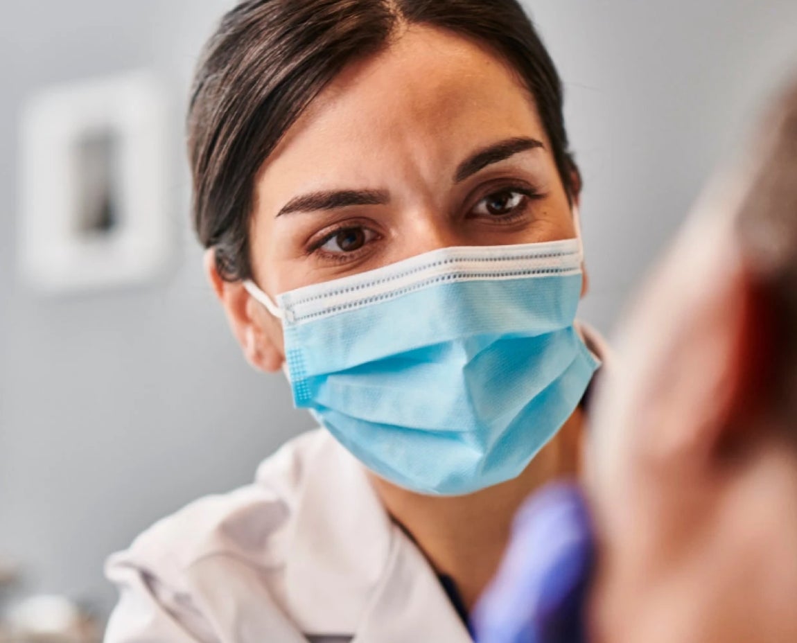  A close-up of an Aspen Dental professional wearing a protective face mask while conducting a detailed examination of a patient, focusing on wisdom tooth care.