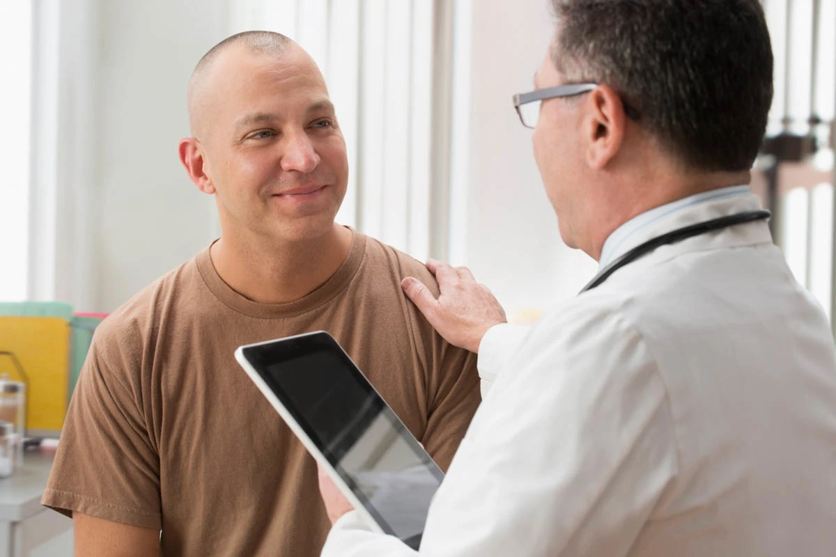 A WellNow Doctor speaks with a veteran in an exam room.