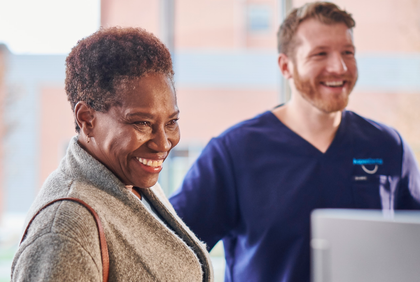 An Aspen Dental patient smiles while a doctor smiles in the background. 