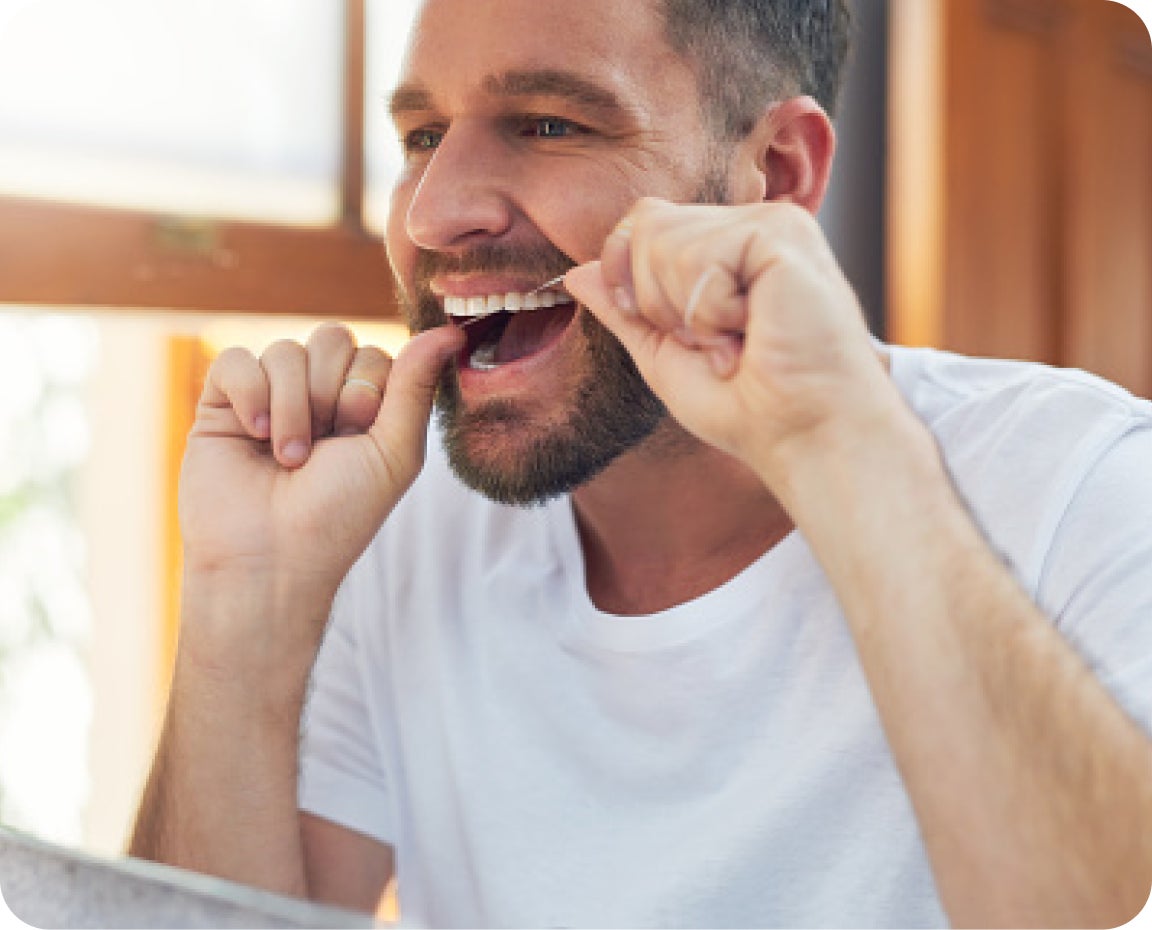 Man checks his gums in the bathroom mirror for signs of gum disease. Emphasizes self-awareness and oral health monitoring.