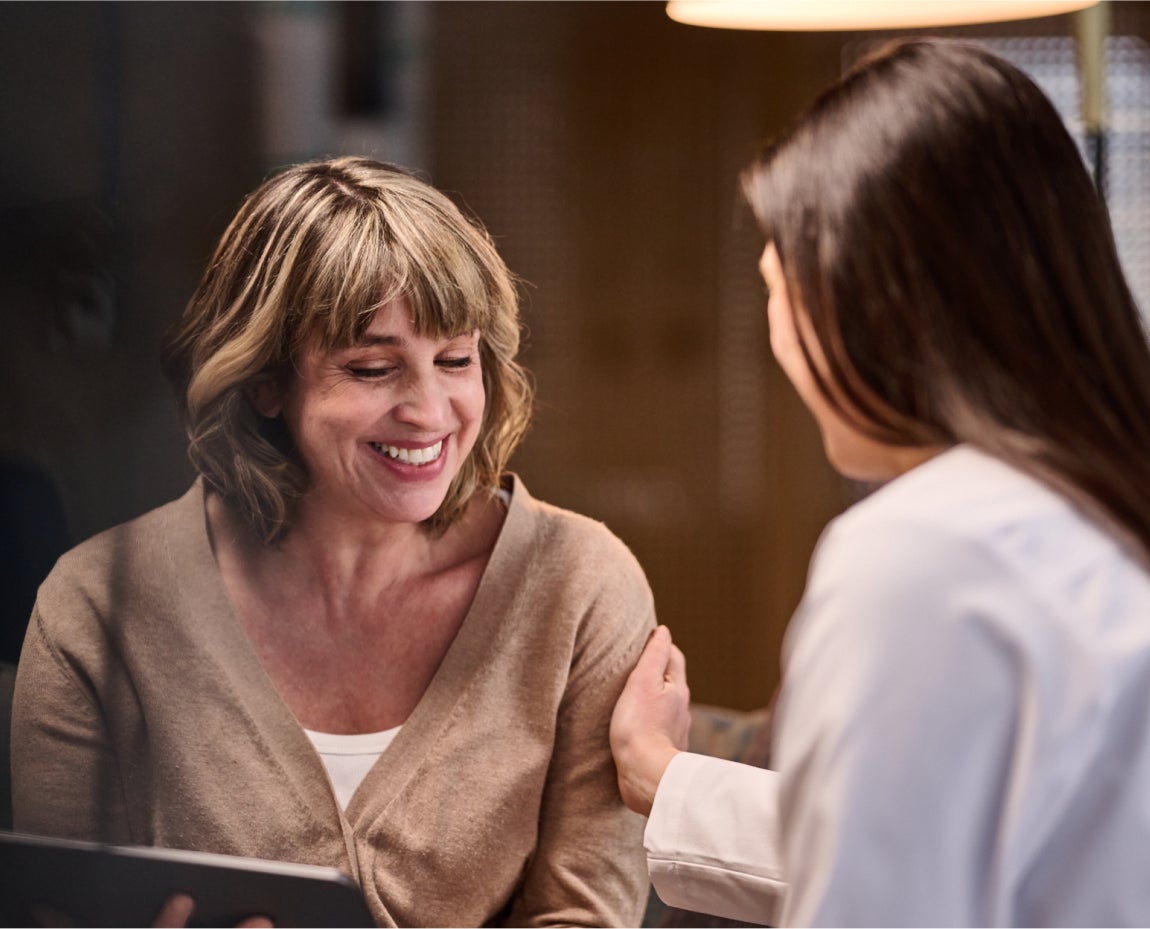 Smiling female patient receiving supportive consultation from an Aspen Dental professional in a caring office environment.