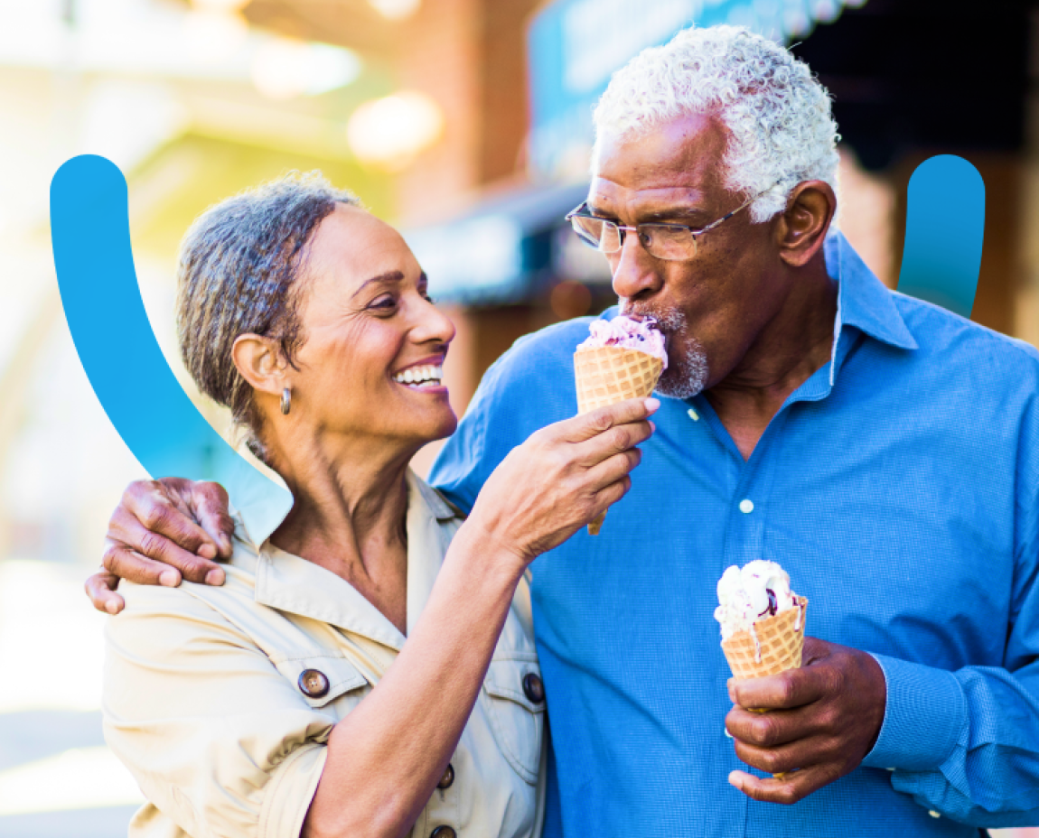 Senior couple smiling and enjoying ice cream cones together outside.