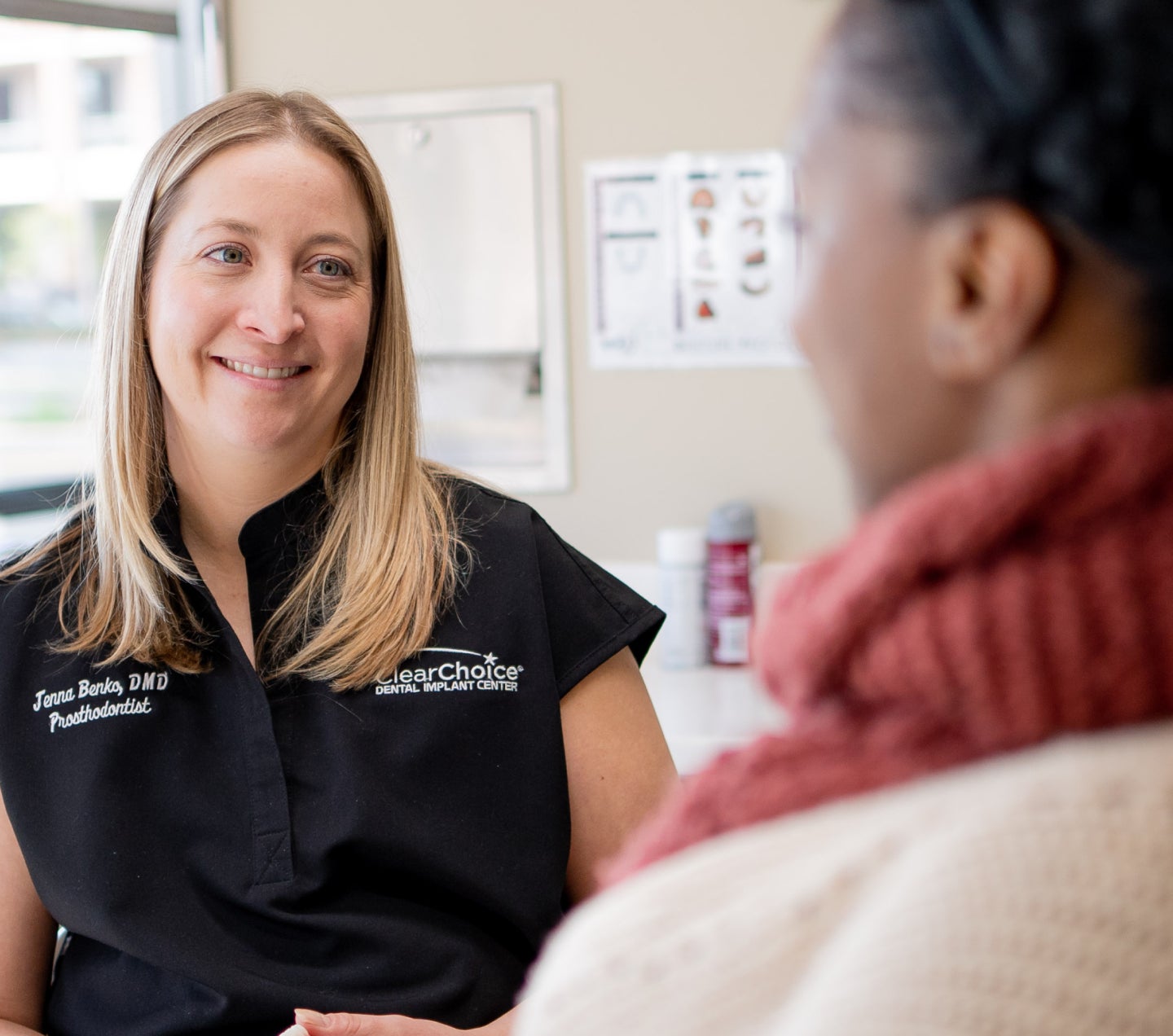 ClearChoice periodontist smiling and discussing dental treatment options with a patient during a consultation in a clinic setting.