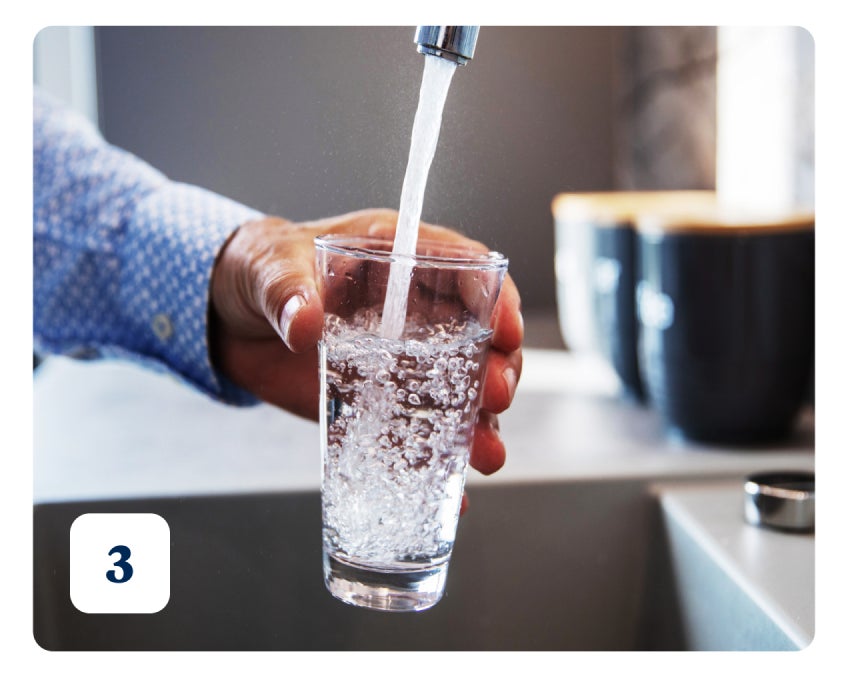 A person fills a glass with water from a tap. Bubbles are visible in the glass, and the number "3" is in the bottom left corner of the image.