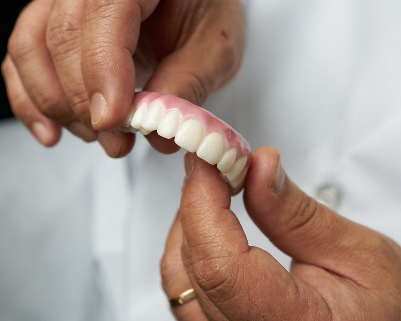 A person is holding a denture in their hands.