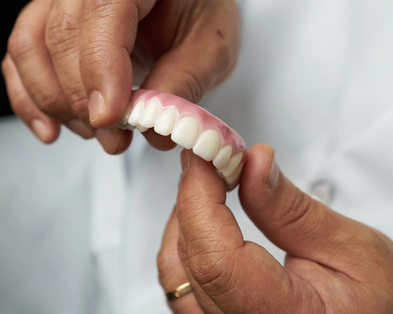 A person is holding a denture in their hands.