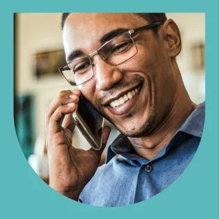 Smiling person on a phone call, representing scheduling an orthodontic consultation.