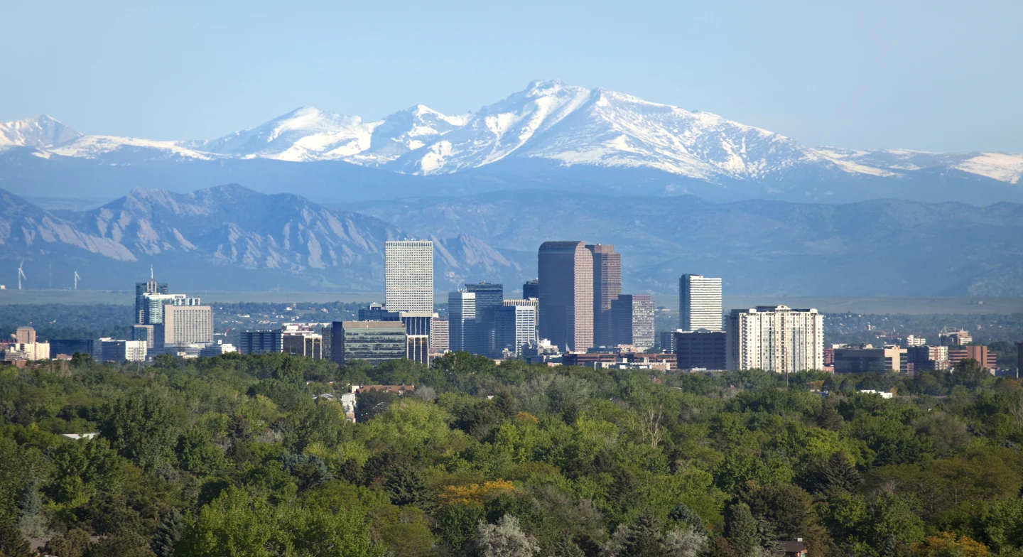 A view of the Denver, CO skyline at midday, with mountains in the background