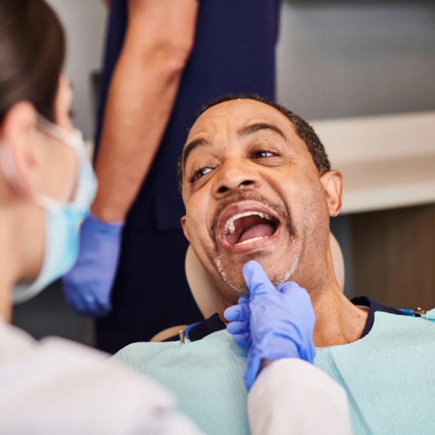 A man reclining in a dental chair with his mouth open, during his periodontal treatment appointment.