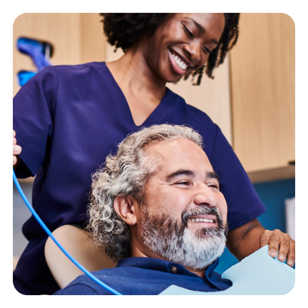  Una asistente dental de Aspen Dental prepara a un paciente mayor para su chequeo en una clínica de Aspen Dental; los dos están sonriendo.