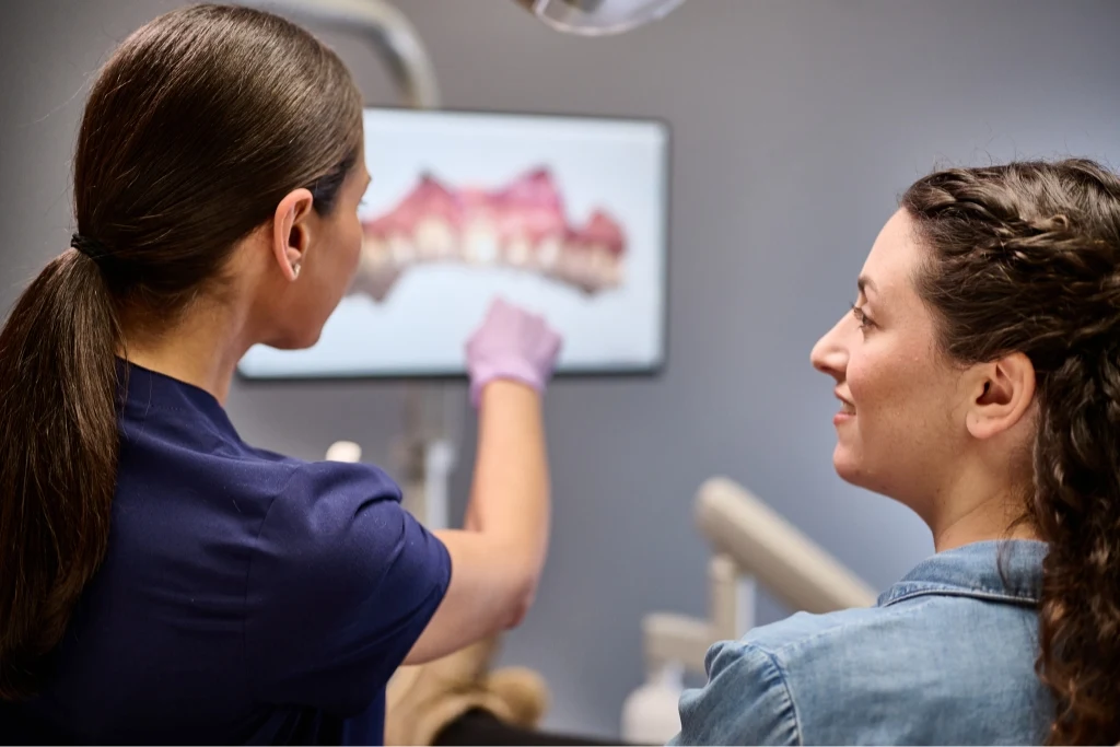 An Aspen Dental Invisalign patient and Doctor look at scans of teeth on a screen. 