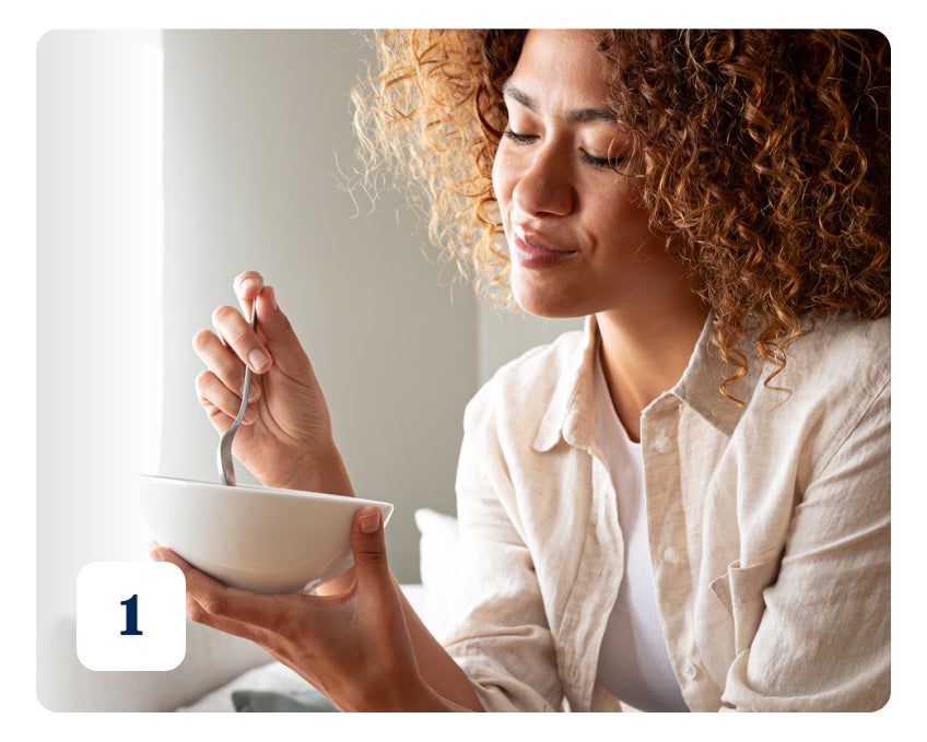 A woman with curly hair holds a white bowl and a spoon, appearing to eat or ready to eat. Number 1 is displayed in the bottom-left corner.