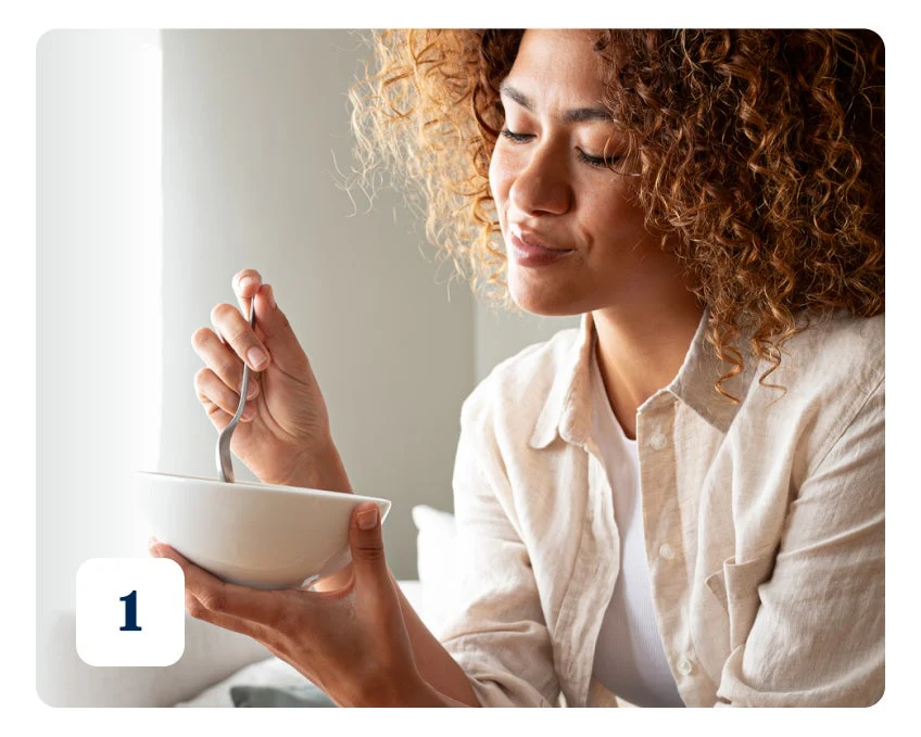A woman with curly hair holds a white bowl and a spoon, appearing to eat or ready to eat. Number 1 is displayed in the bottom-left corner.