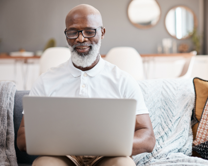 An Aspen Dental patient smiling while typing on a laptop.