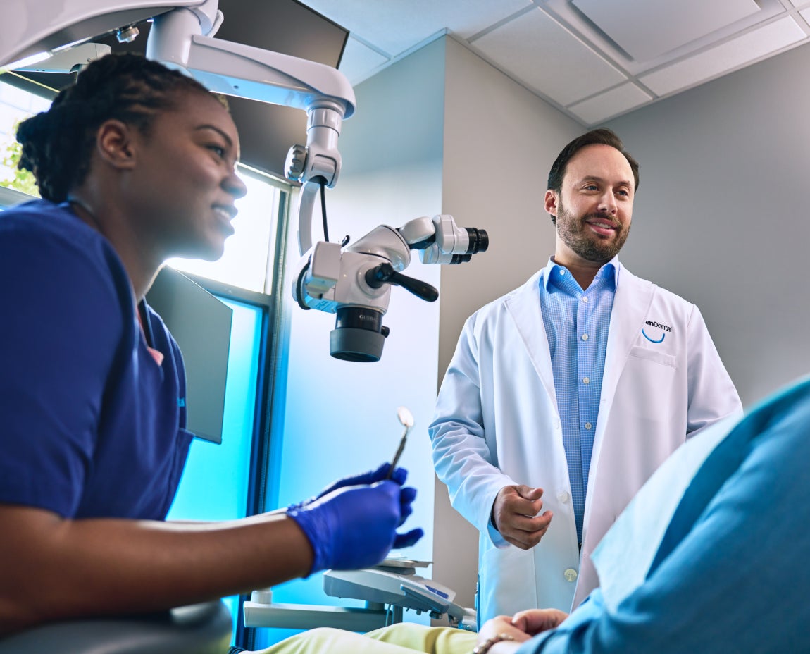 Aspen Dental dentist and assistant discussing care with a patient, showcasing modern dental technology and a professional, welcoming environment.