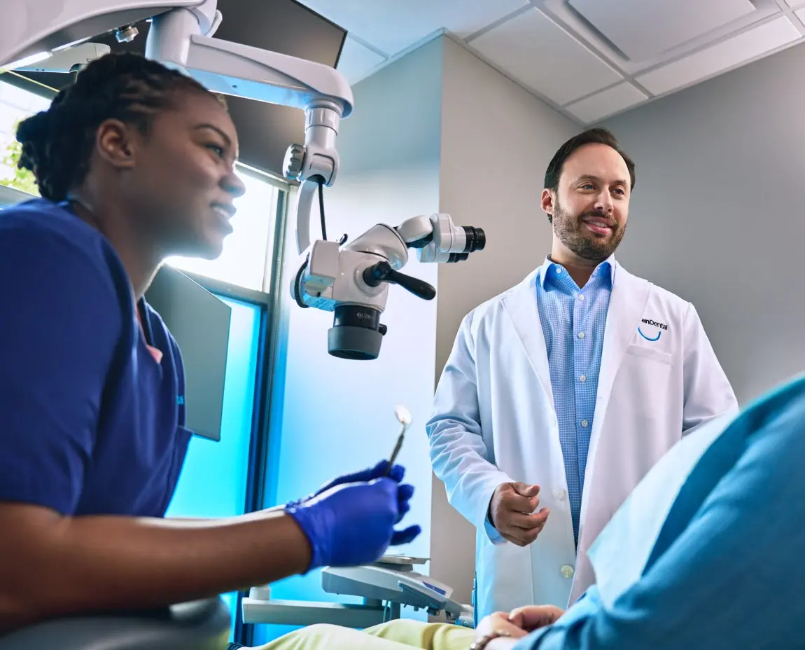 Aspen Dental dentist and assistant discussing care with a patient, showcasing modern dental technology and a professional, welcoming environment.