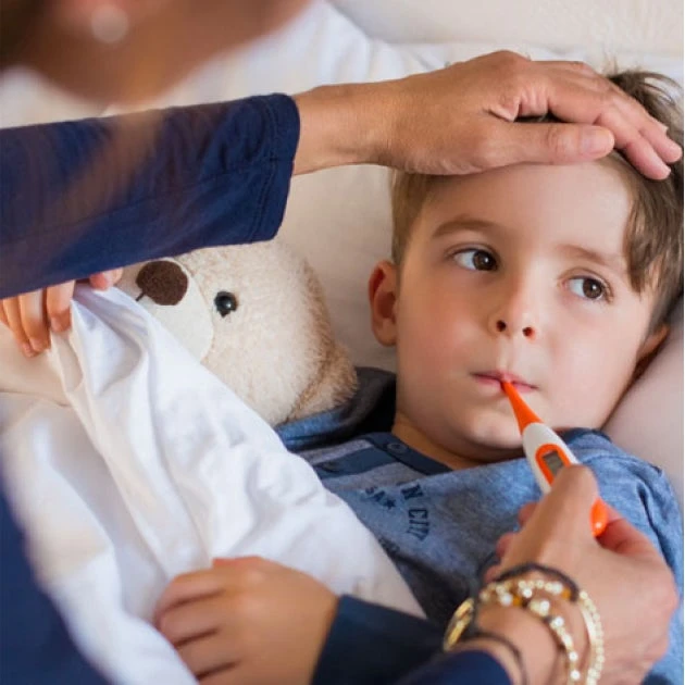 A woman is taking a child 's temperature with a thermometer