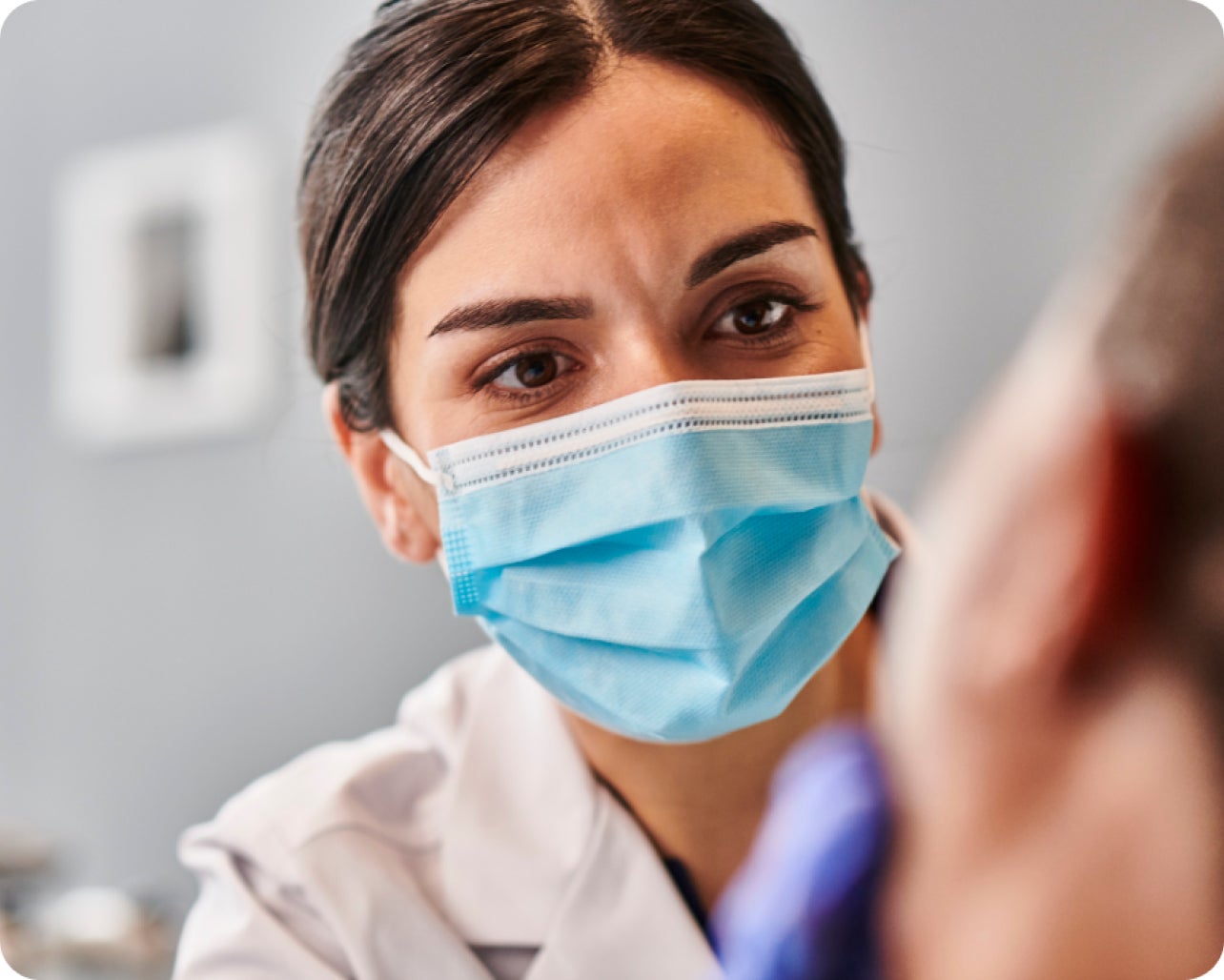  Aspen Dental dentist wearing a mask, attentively examining a patient.