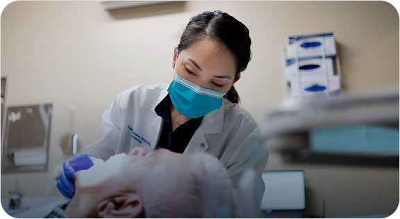 A ClearChoice oral and maxillofacial surgeon performing a dental bone graft procedure on her patient.