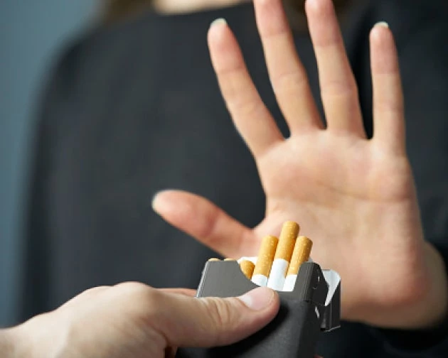 An image of a patient saying no to a pack of cigarettes by raising a hand.