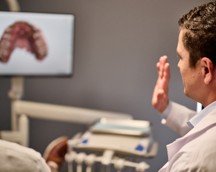 An Aspen Dental doctor and patient look at scans on a computer monitor. 