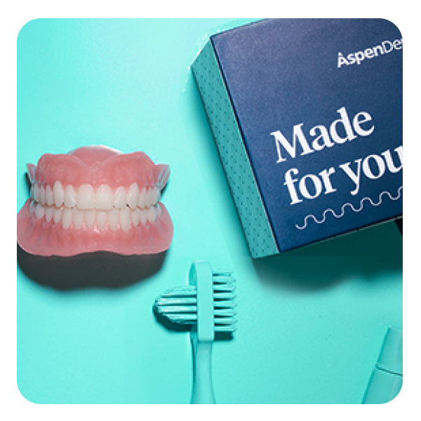 Una foto que muestra un cepillo de dientes, un juego completo de dentaduras personalizadas y un kit "Hecho para ti" de Aspen Dental, con un fondo color teal.