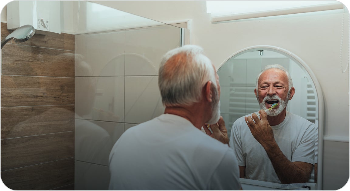 A man in a white shirt brushing his teeth and keeping good oral hygiene to prevent potential risks of oral and systemic diseases.