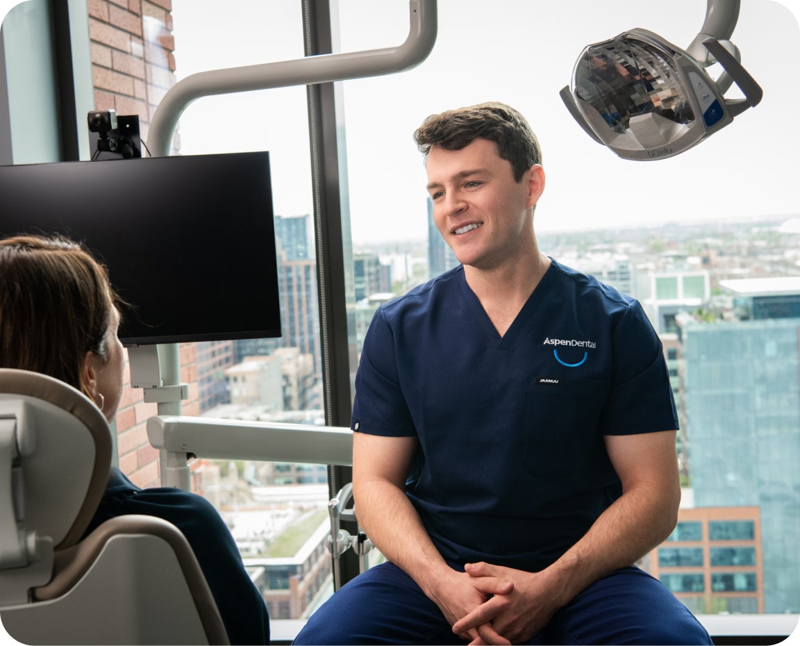 Aspen Dental team member discusses periodontal disease treatment with patient using x-rays and dental tools in a modern office setting.