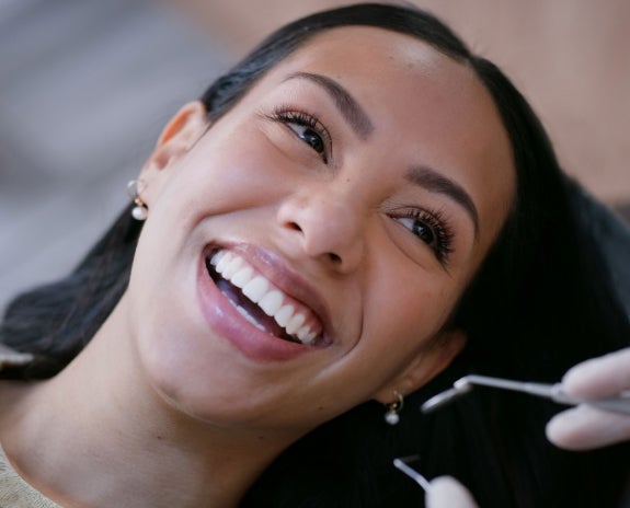 A close-up of a smiling patient at Aspen Dental during a dental veneers appointment, highlighting confidence and comfort in professional dental care.