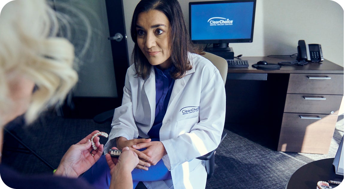A ClearChoice doctor in a white lab coat explaining to a female patient her treatment options, her dental implant process and related costs.