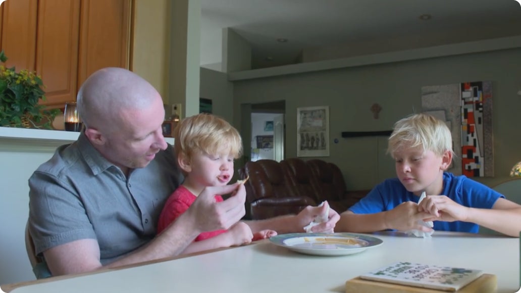 Neal, a ClearChoice patient, sitting at the kitchen table feeding his two boys.