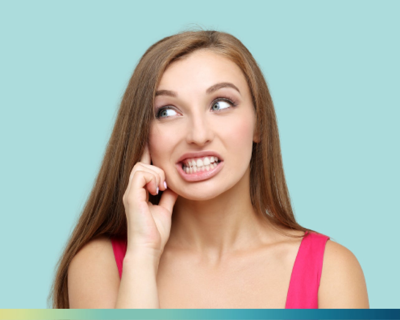 A woman with long brown hair and wearing a pink top has a slightly tense expression, clenching her teeth while awake, and touching her face. The background is a solid light blue.