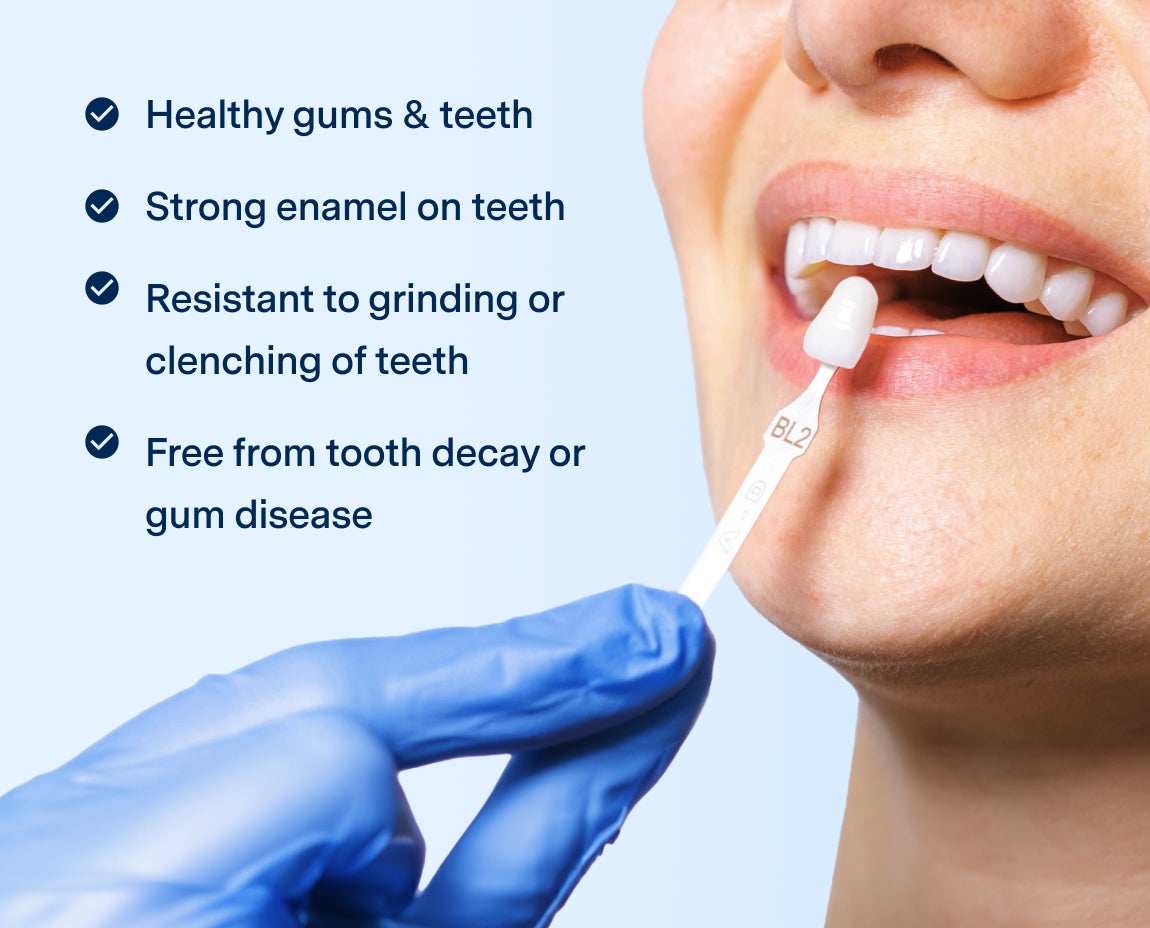 A dentist holds a shade guide next to a patient's smiling mouth, highlighting healthy gums, strong enamel, resistance to grinding, and absence of decay or gum disease.